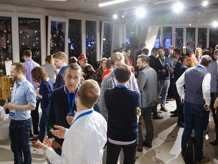 Die Gäst:innen des Events stehen zusammen und unterhalten sich in lockerer Atmosphäre