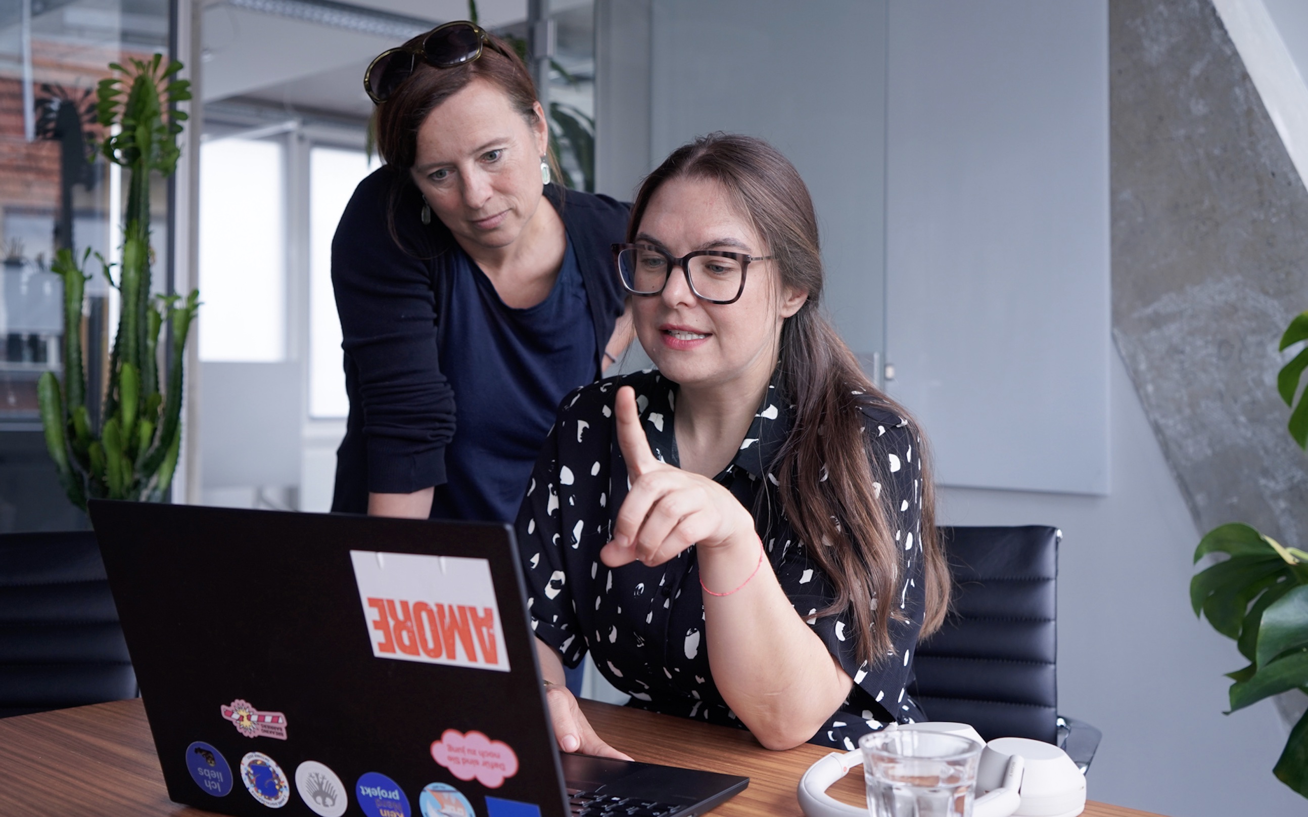 Interviewee Lisa in conversation with a colleague; both look into Lisa's laptop and she explains what is on the screen