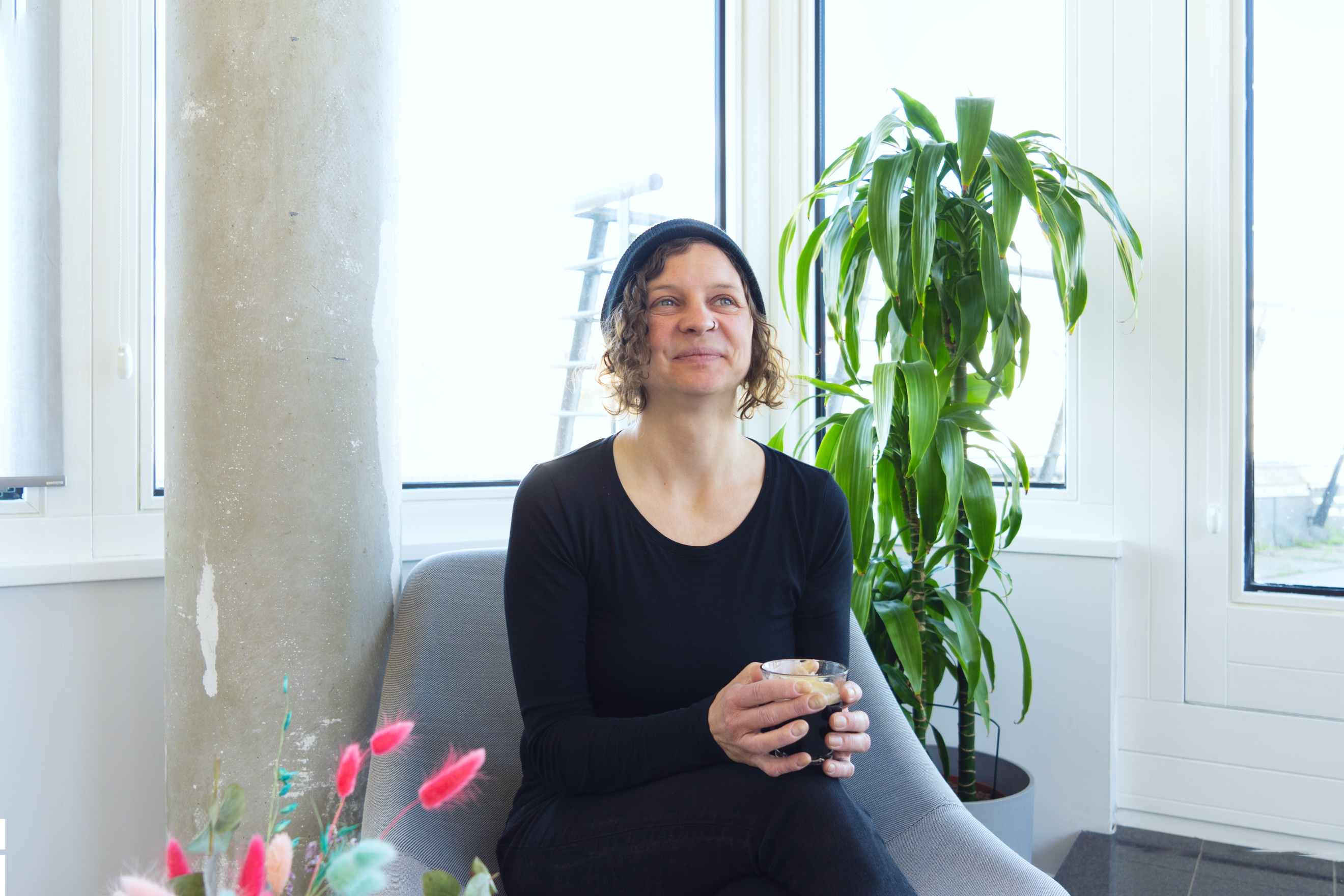 Interviewpartnerin Sonja sitzt lächelnd auf einem Sessel im Büro des DigitalService