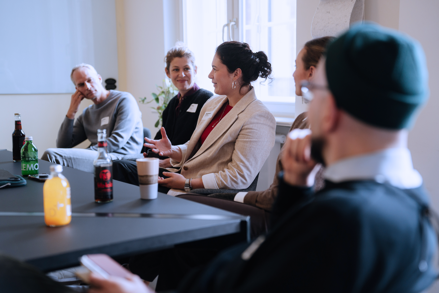 Mehrere Menschen sitzen an einem Konferenztisch und unterhalten sich.
