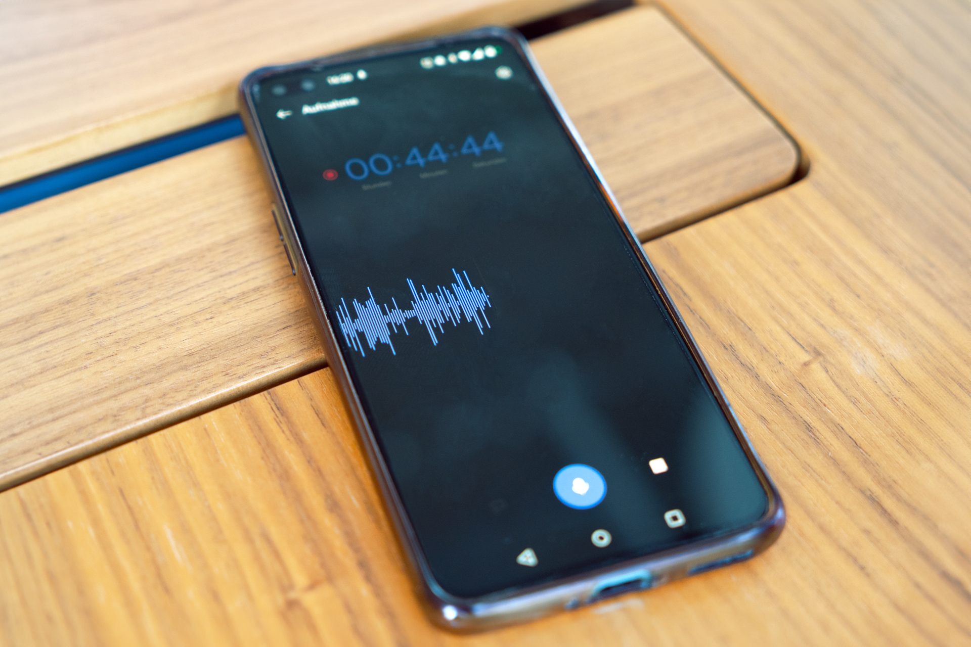 Ein Handy liegt auf dem Tisch. Eine Rekorder-App ist geöffnet, die ein 44 Minuten und 44 Sekunden langes Gespräch aufgezeichnet hat