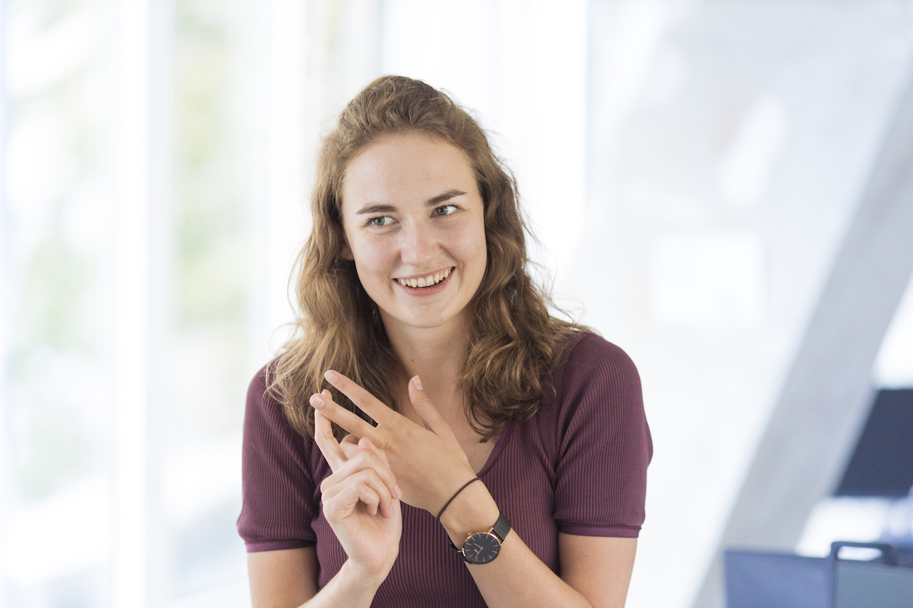 Frederike gestures that she is counting to three with both hands.