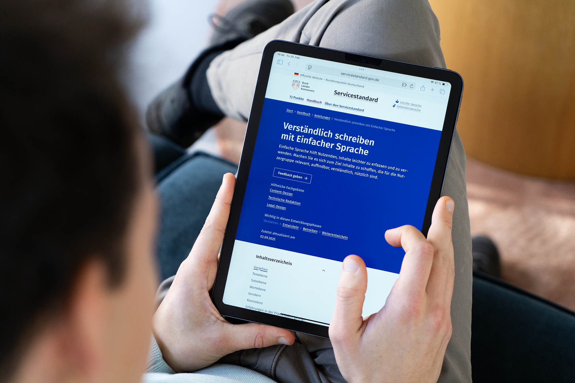 Eine Person hält einen Tablet-Computer, der eine Anleitung zum verständlichen Schreiben mit einfacher Sprache im Rahmen des Servicestandards der deutschen Verwaltung zeigt