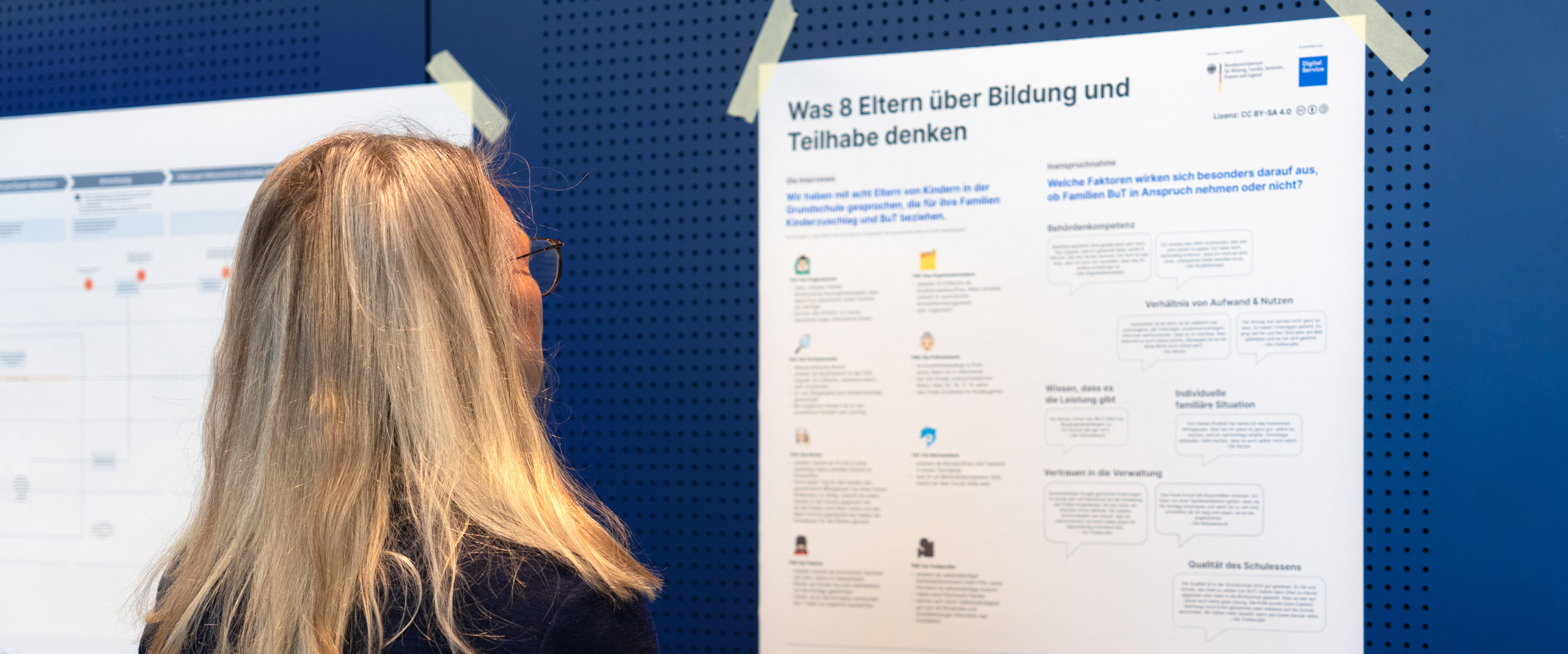 A woman is looking at a poster displaying the results of a user survey on educational and participation services.