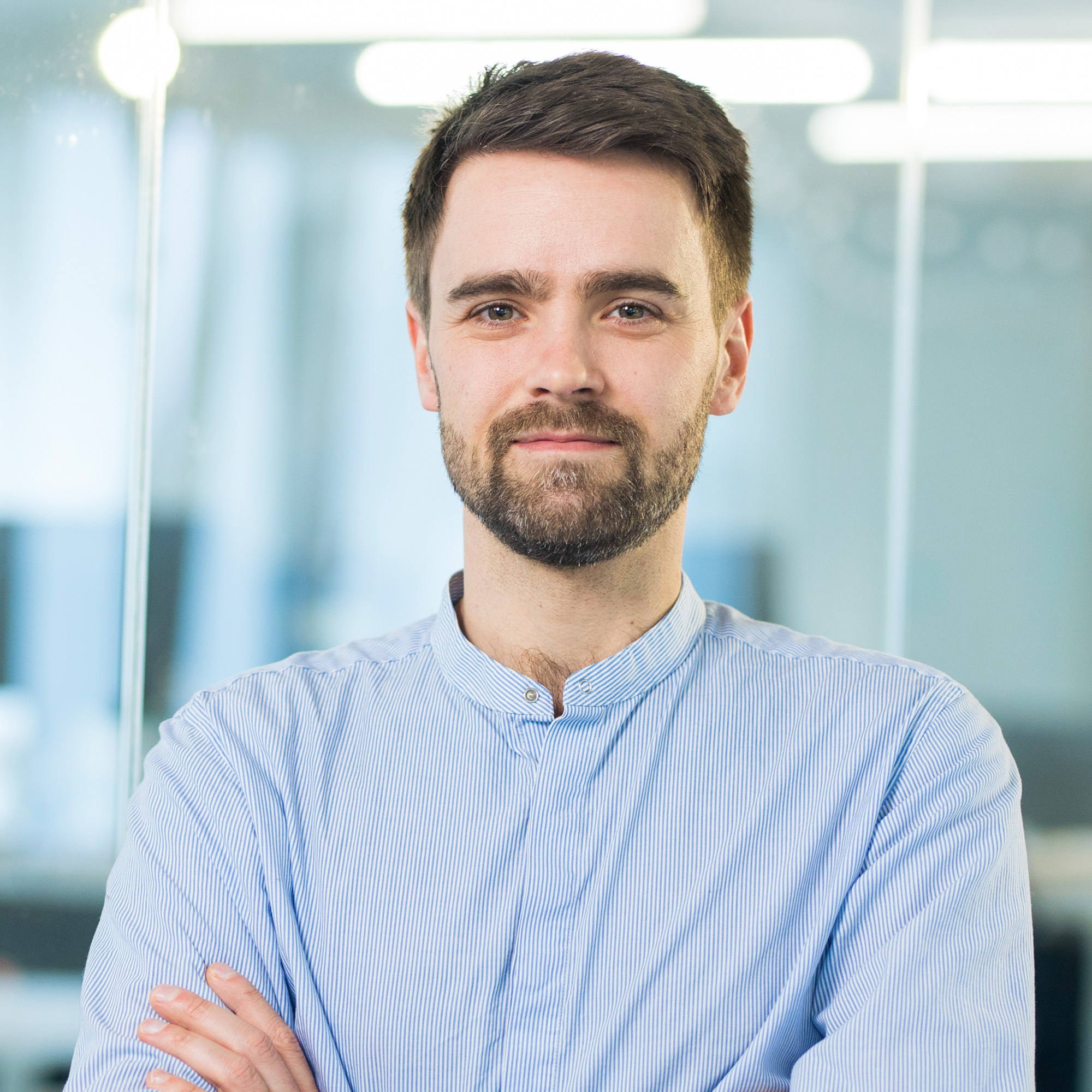 Head of Engineering Christian Kaatz in einem blauen Hemd vor einer Glaswand im Büro des DigitalService