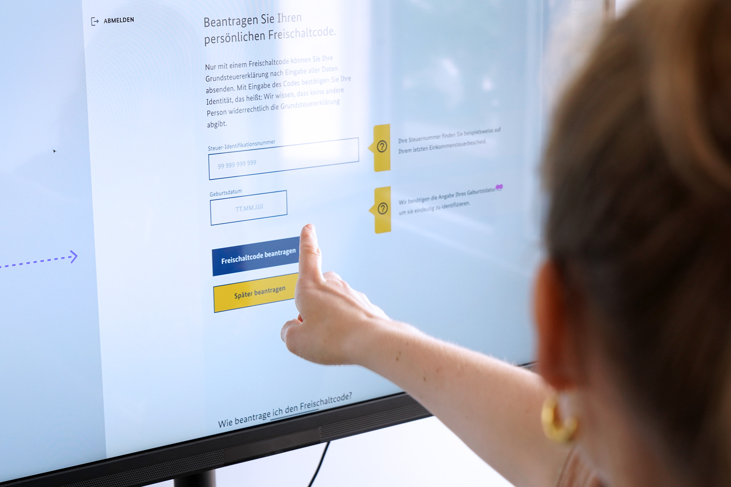 Eine Person zeigt mit dem Finger auf einen Bildschirm, der den Entwurf eines Online-Formulars mit mehreren Eingabefeldern und Knöpfen zeigt