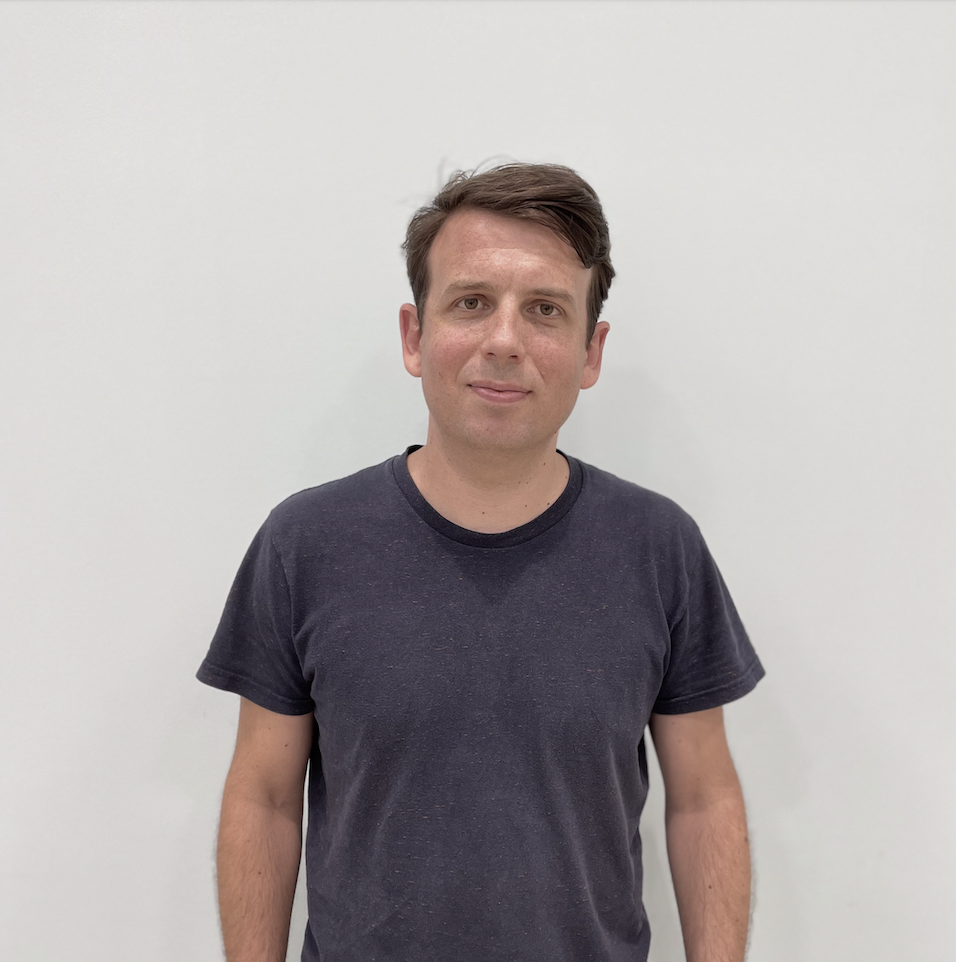 Christoph Böhmer, Senior Product Manager beim DigitalService, steht leicht lächelnd vor einer weißen Wand; er hat kurze braune Haare und trägt ein dunkelblaues T-Shirt