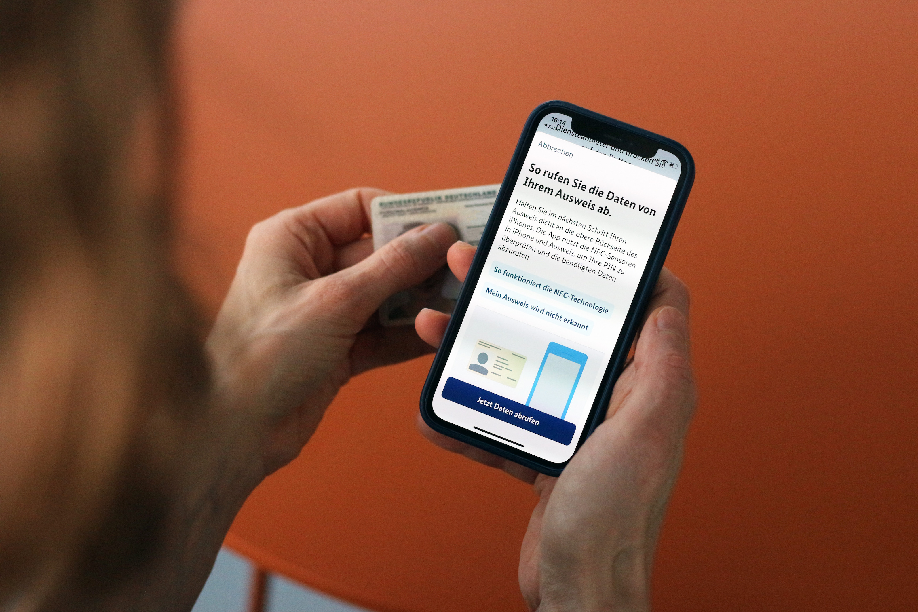 During the identification process with BundesIdent, a person holds an ID card and a cell phone with the opened application in their hands.