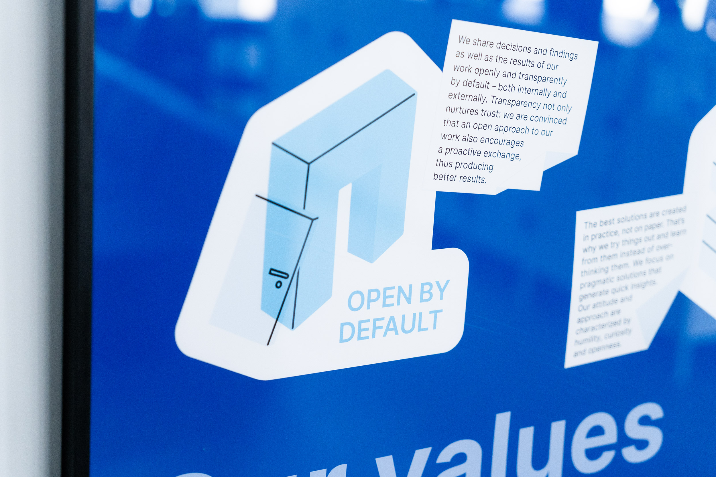 Nahaufnahme eines blauen Posters in englischer Sprache mit einer Illustration eines stilisierten Türrahmens und der Überschrift „Arbeite offen“ mit einem kurzen Erklärungstext