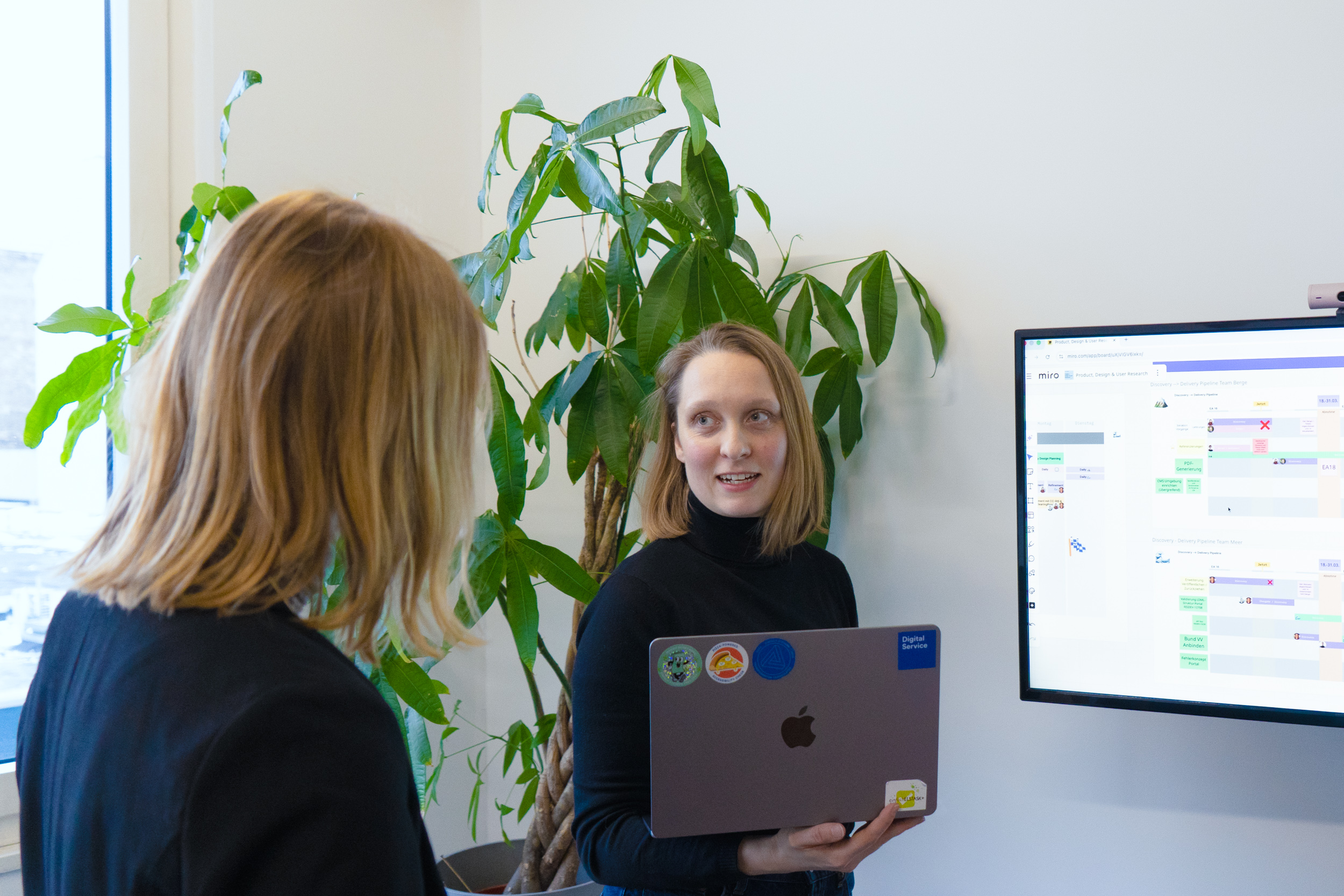 Die Autorinnen im Gespräch vor einem großen Bildschirm auf dem unterschiedliche Projektphasen zu sehen sind