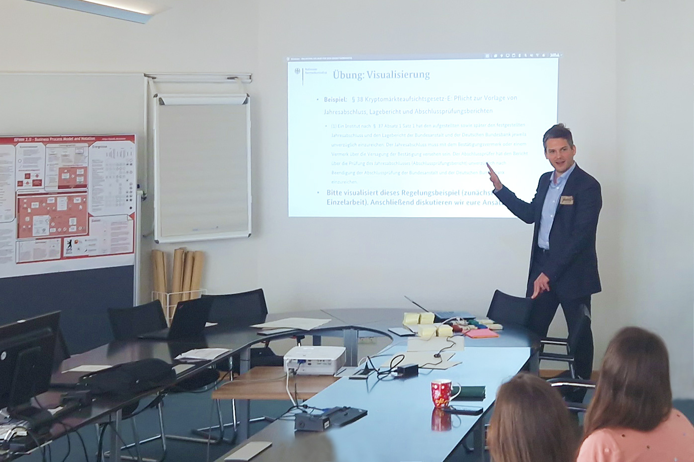 Yannick Vogel gibt einen Workshop im Bundesministerium der Finanzen. Ein Beamer wirft eine „Übung für Visualisierungen“ an die Wand, Yannick Vogel zeigt darauf und erklärt dem Publikum die Übung.