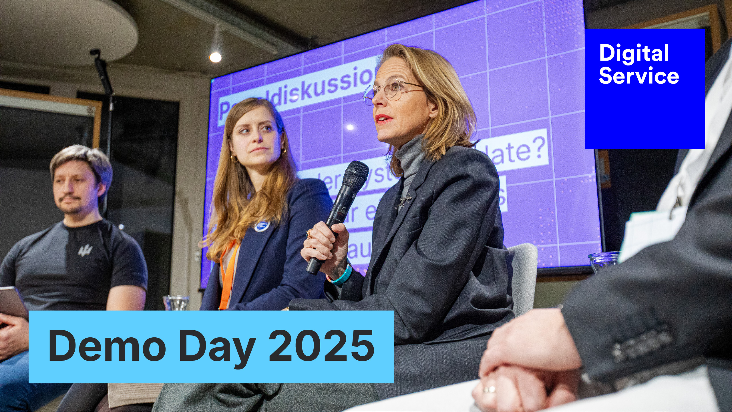 Panel discussion at “Demo Day 2025”. Julia Jaekel, media manager and co-initiator of the „Initiative für einen handlungsfähigen Staat“ speaks into the microphone. In the background, a presentation slide with the “DigitalService” logo.