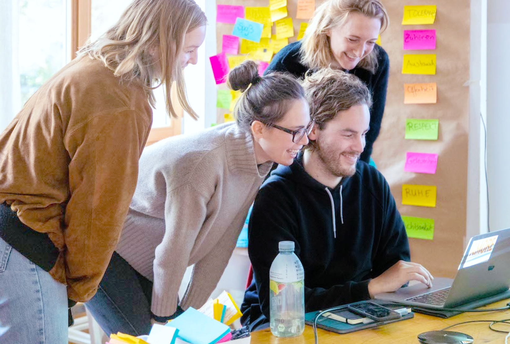 Mehrere Mitglieder des Fellowship-Teams und eine Fellow schauen sich gemeinsam etwas auf einem Laptop an