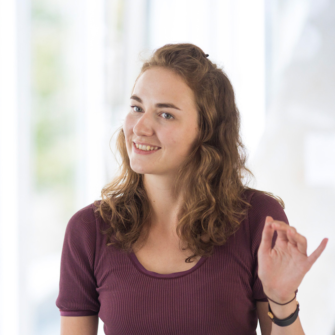 Frederike is standing in the DigitalService office, gesturing with her left hand.