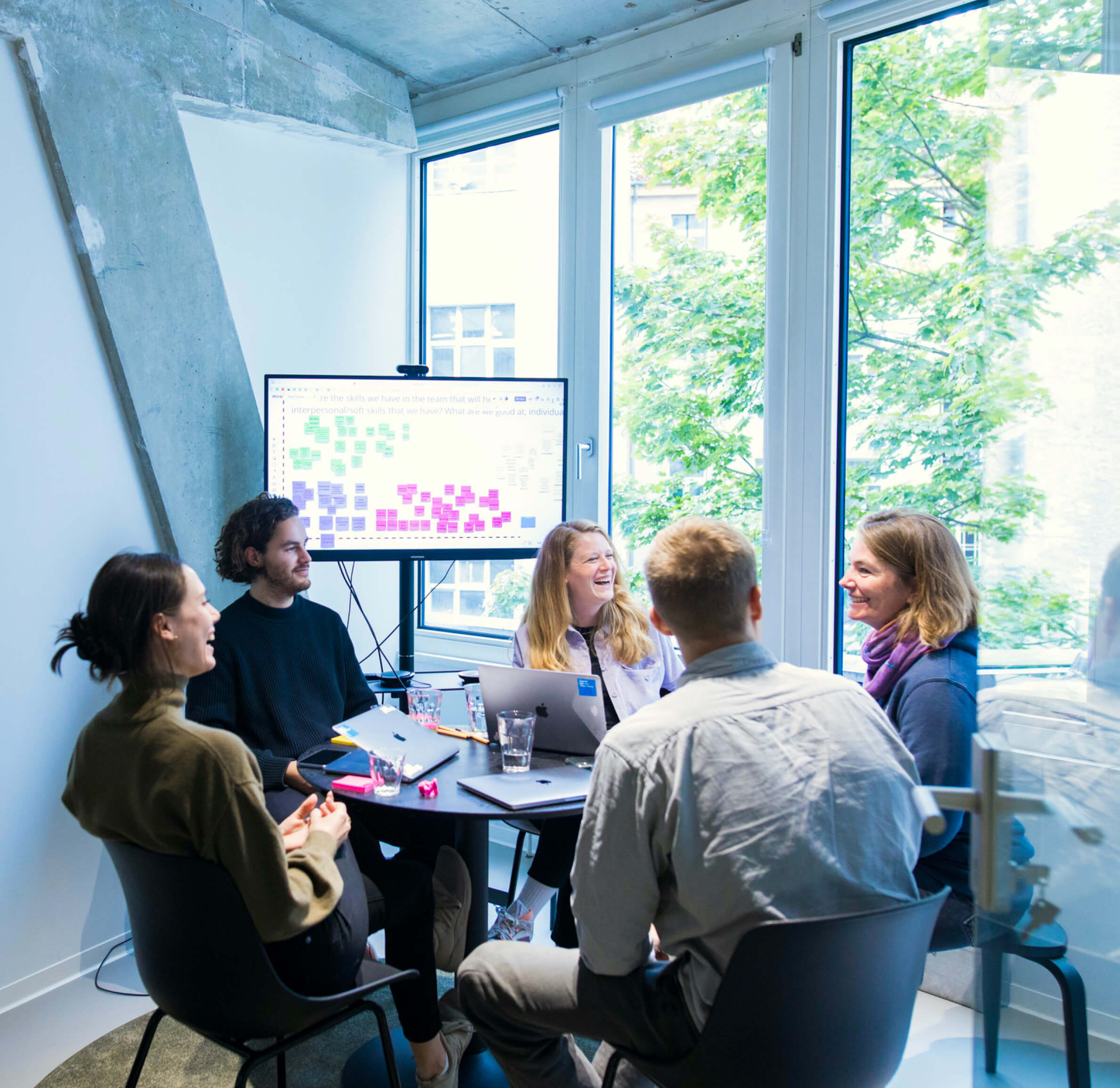 DigitalService employees sit in a meeting room and happily discuss things with each other