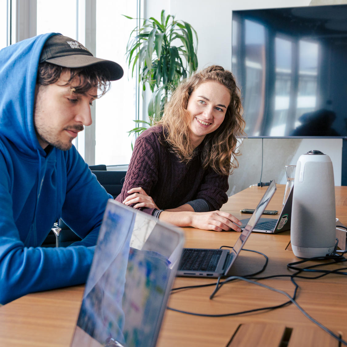 Zwei Mitarbeitende des DigitalService sitzen an einem Bürotisch in lockerer Atmosphäre und arbeiten an ihren Laptops
