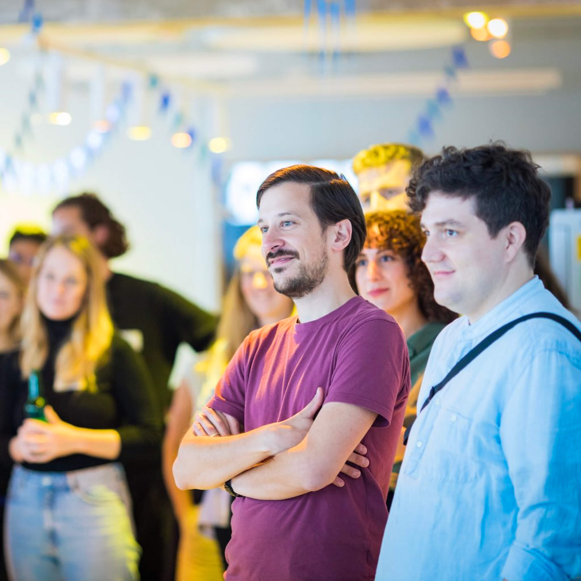 DigitalService employees stand together in the office kitchen and listen to a presentation