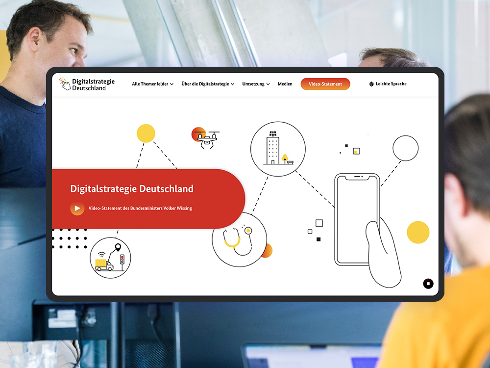 The homepage of the Digital Strategy Germany website can be seen on a tablet; the DigitalService office can be seen in the background as a visual style element