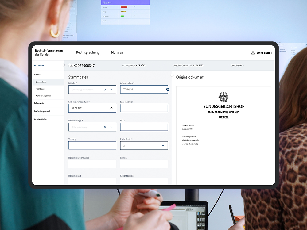 Ein Mockup des Rechtsinformationssystems NeuRIS auf einem Tablet; als visuelles Stilmittel sieht man im Hintergrund das Büro des DigitalService