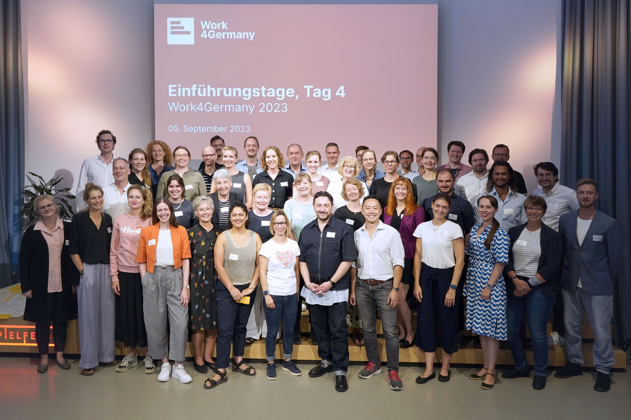 All participants of the 4th Work4Germany year stand together on one stage