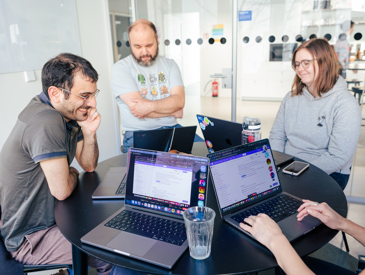 DigitalService employees sit together at a table and work; they look at their laptops and communicate with others virtually.